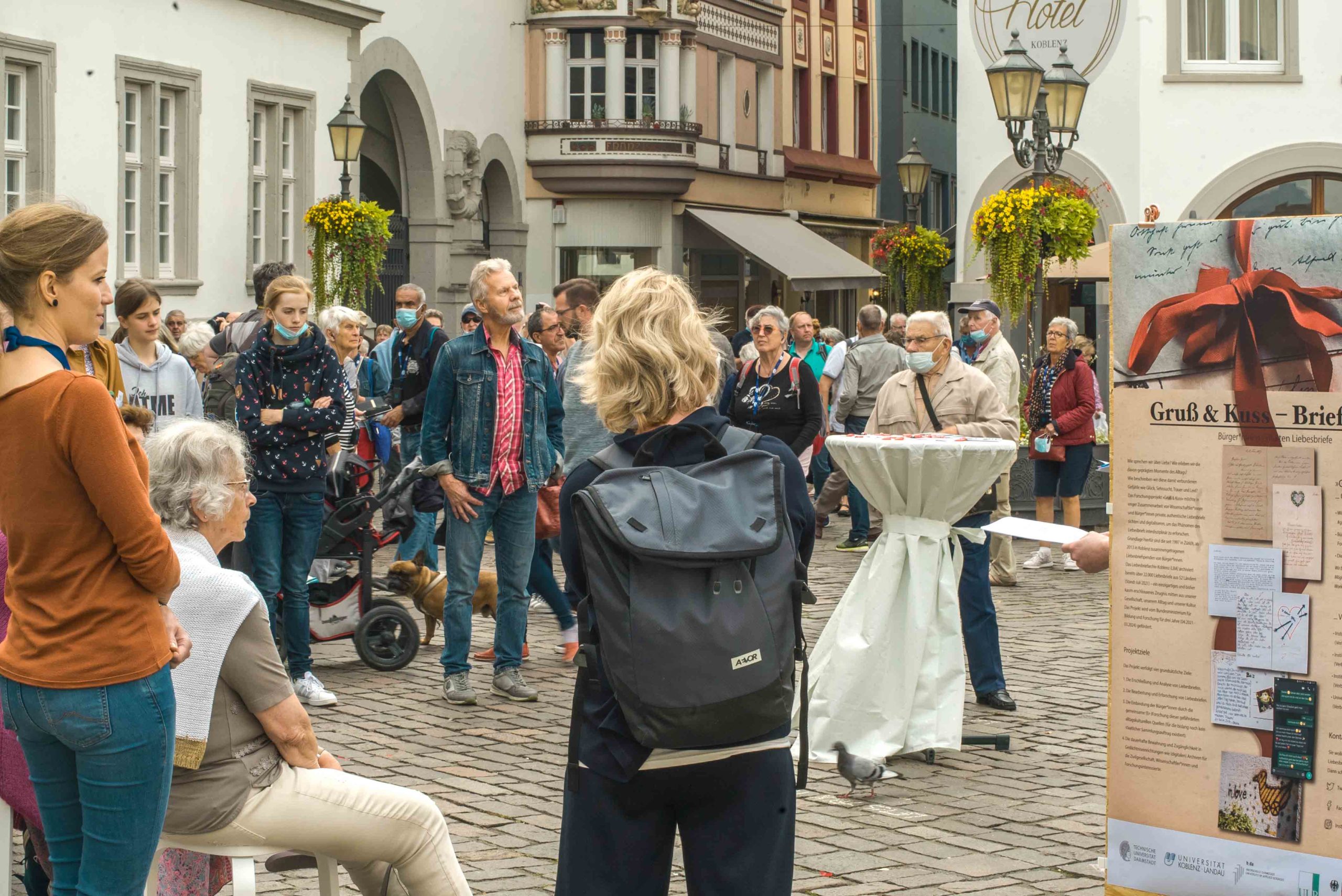 Menschen hören auf dem Jesuitenplatz einem Vortrag über das Liebesbriefarchiv und das "Gruß & Kuss"-Projekt zu