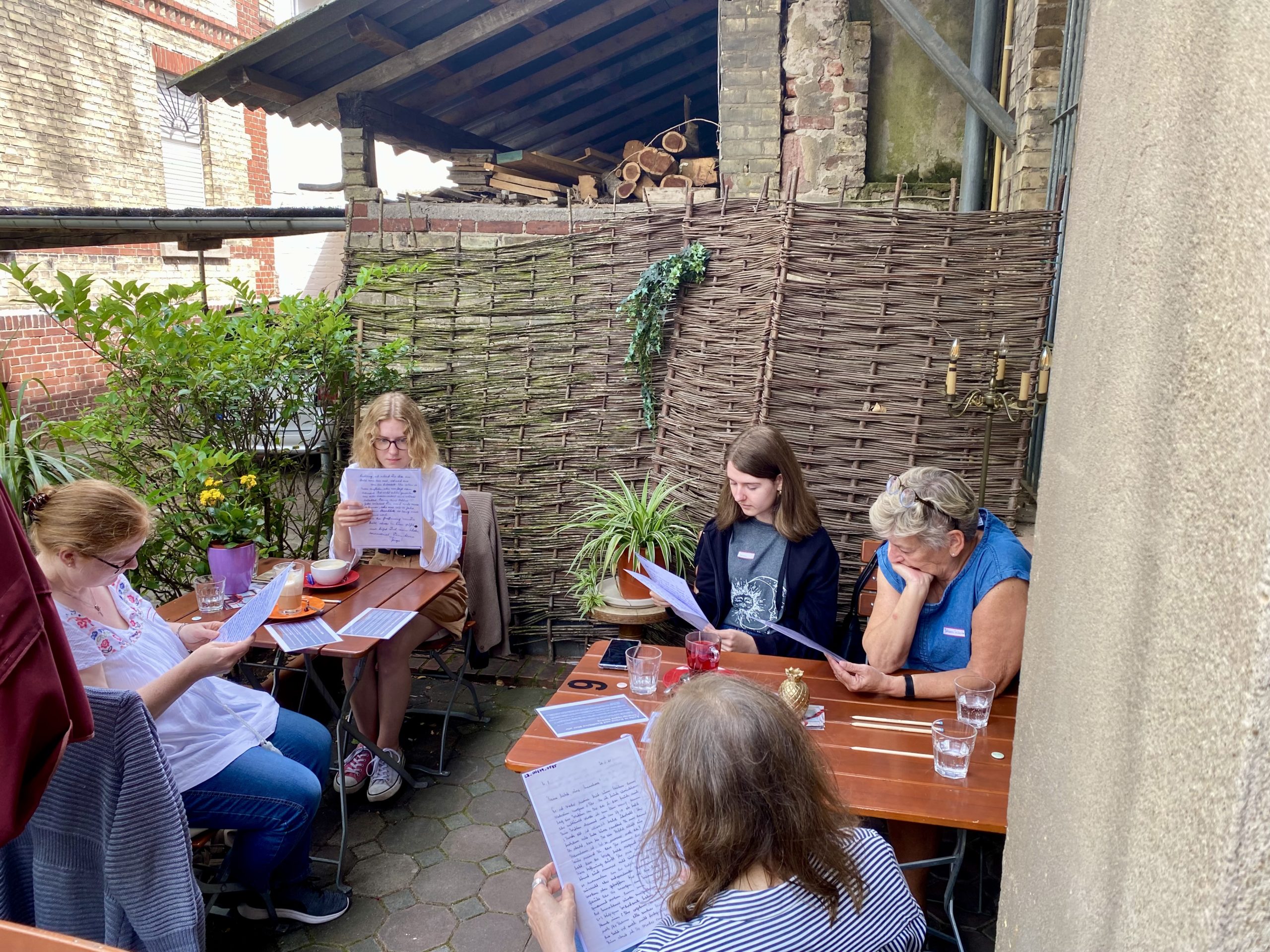 Citizen Scientists lesen an Tischen auf der Terrasse des See You Cafés Liebesbriefe