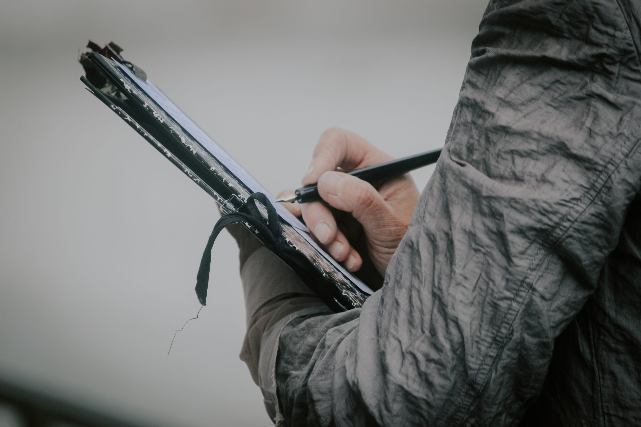 Eine Person schreibt mit einem Füllfederhalter auf einem Klemmbrett