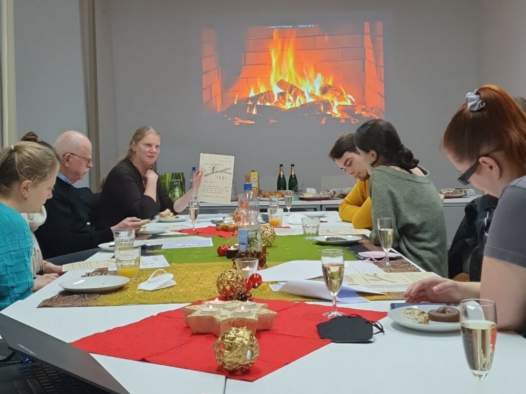 Citizen Scientists und Verbundkoordinatorin Prof. Andrea Rapp sitzen mit Liebesbriefen, Essen und Getränken an einem Tisch im Residenzschloss der TU Darmstadt