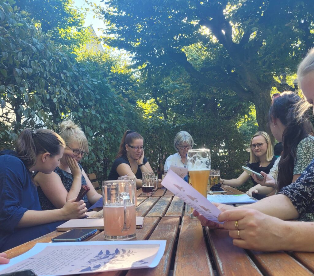 Bürgerwissenschaftler*innen sitzen im Schlossgarten am Tisch und lesen Liebesbriefe.