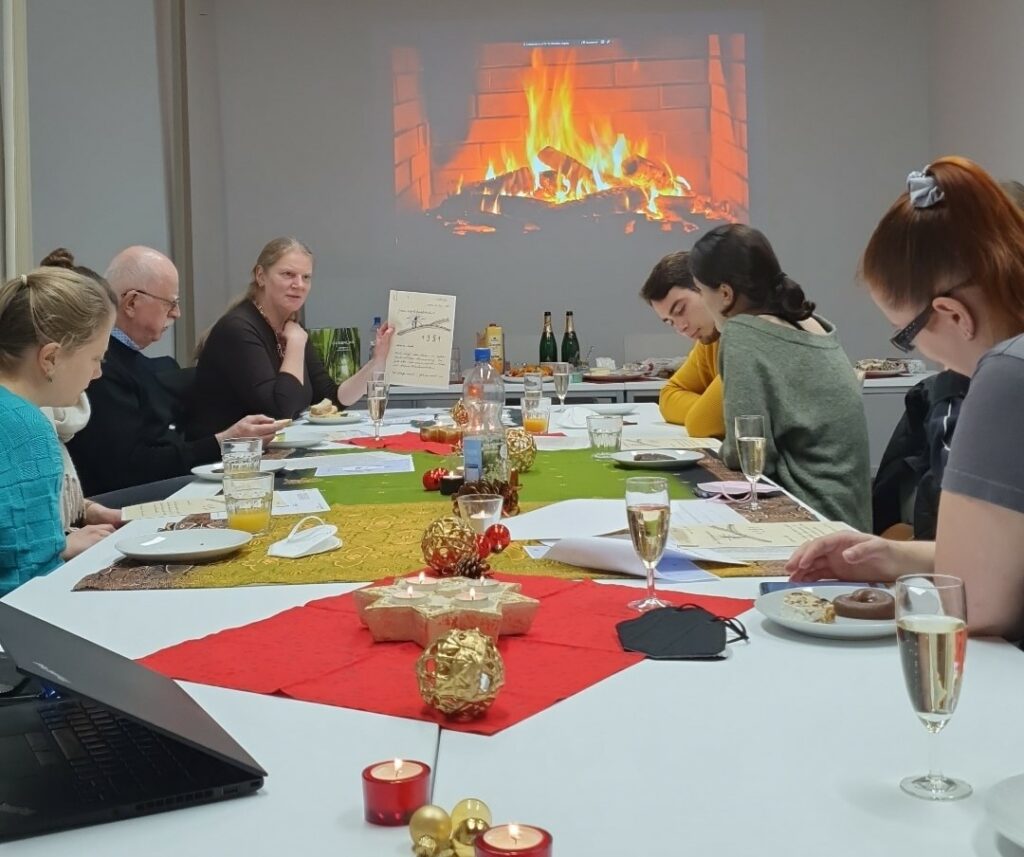 Bürgerwissenschaftler*innen sitzen mit Prof. Andrea Rapp an einem weihnachtlich geschmückten Tisch und lesen Liebesbriefe.